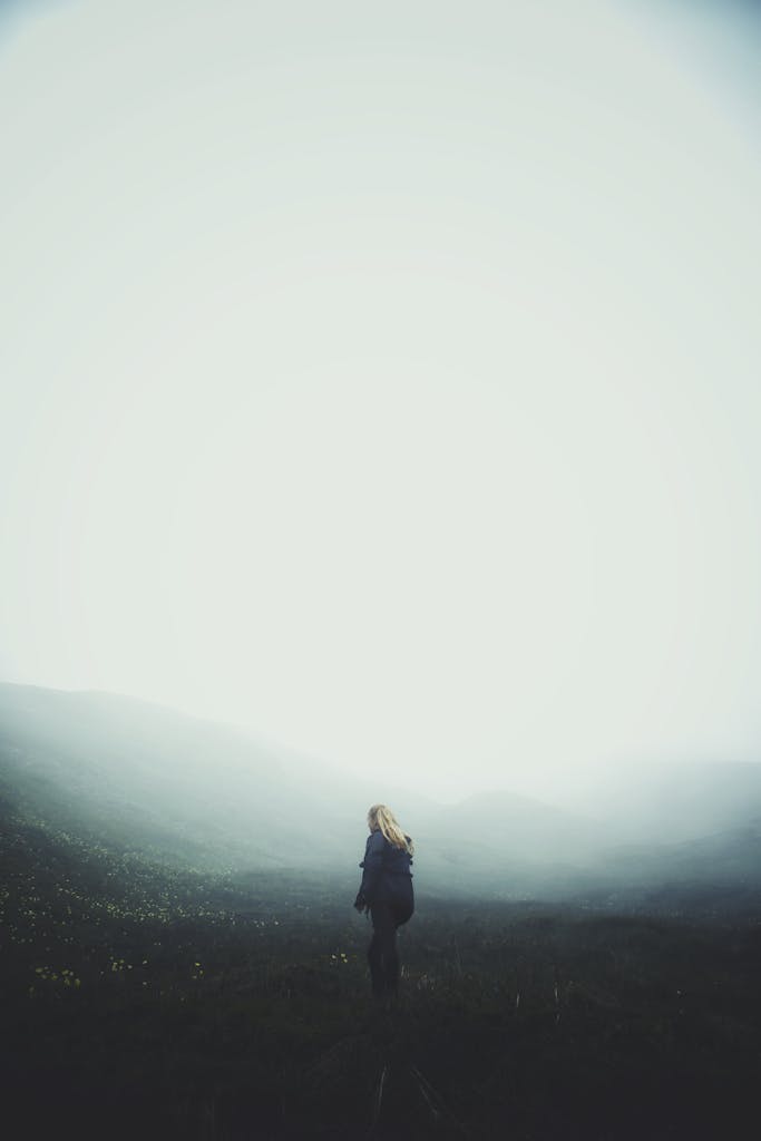 Woman Wearing Blue Jacket Standing on Grass Fiels'